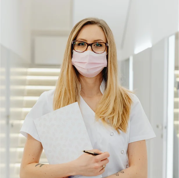 Healthcare worker wearing a mask and holding a clipboard.