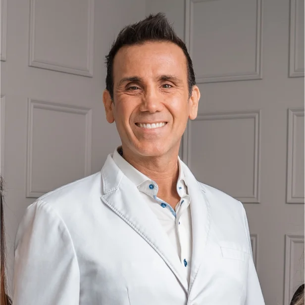 Smiling man in a white blazer posing indoors.