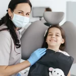 Dentist with a child patient smiling in a dental chair.