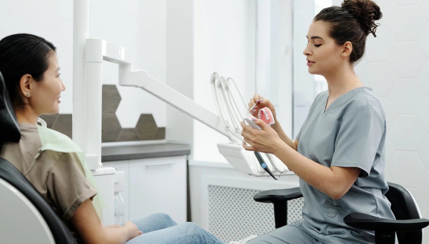 A dentist prepares dental tools while a patient waits.