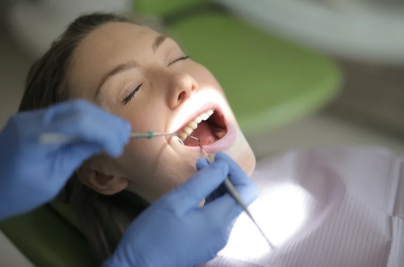 Dentist examining a patient's teeth with dental tools.