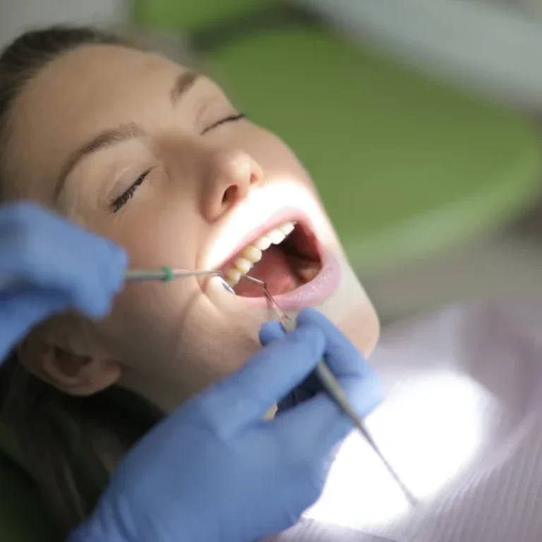 Dentist examining a patient's teeth with dental tools.