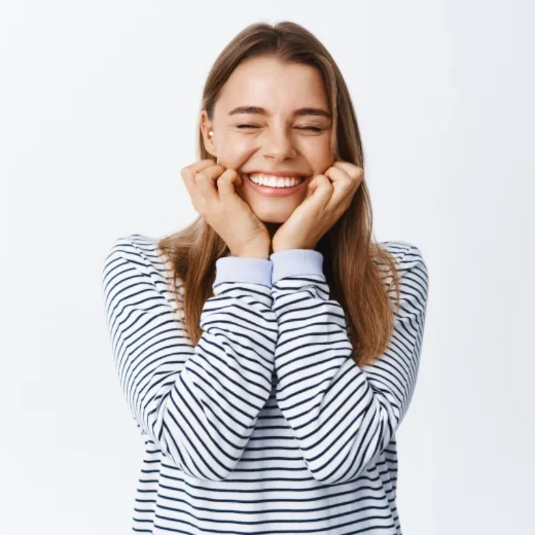A joyful woman smiling with eyes closed, wearing a striped shirt.